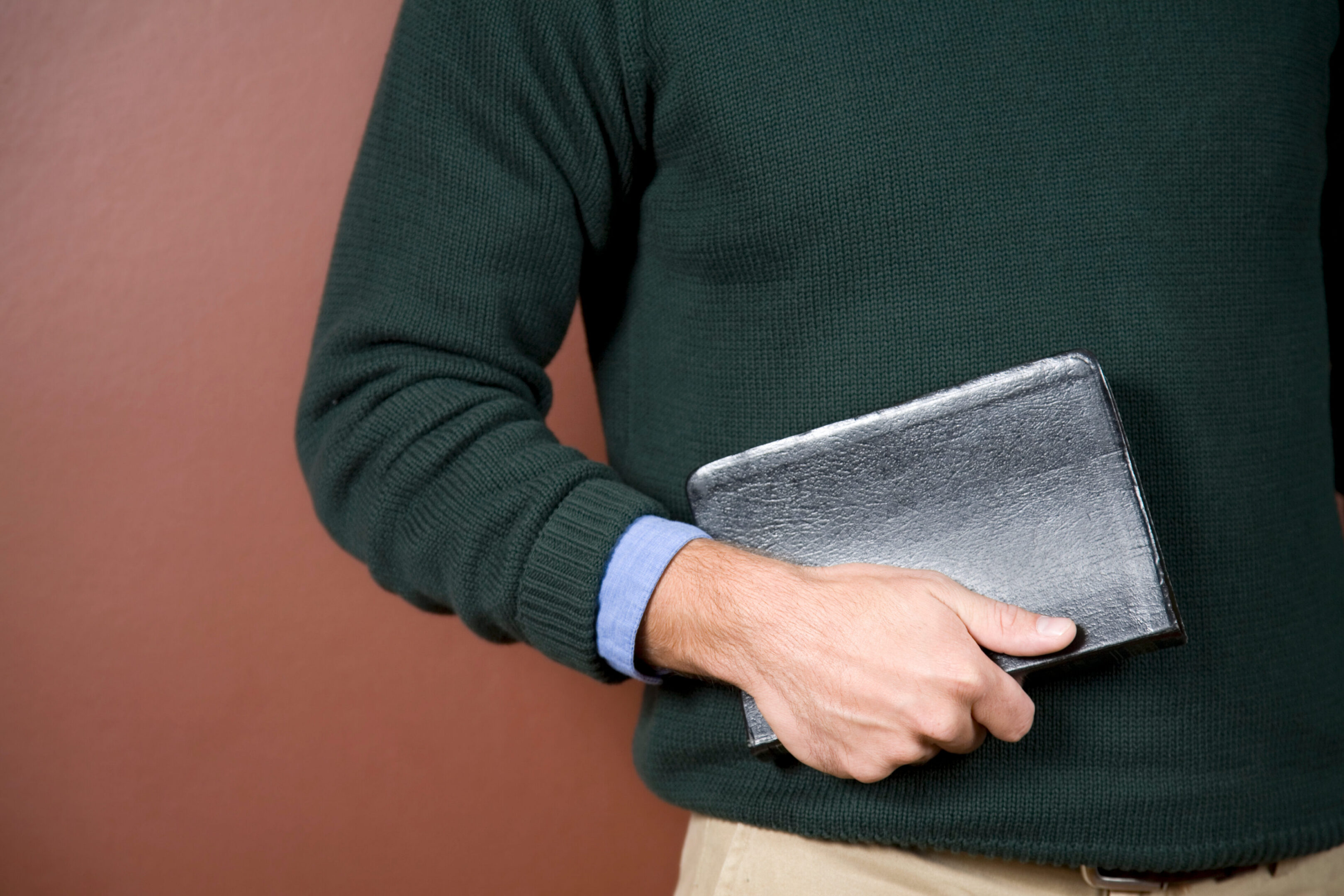 Person holding a book against brown background.