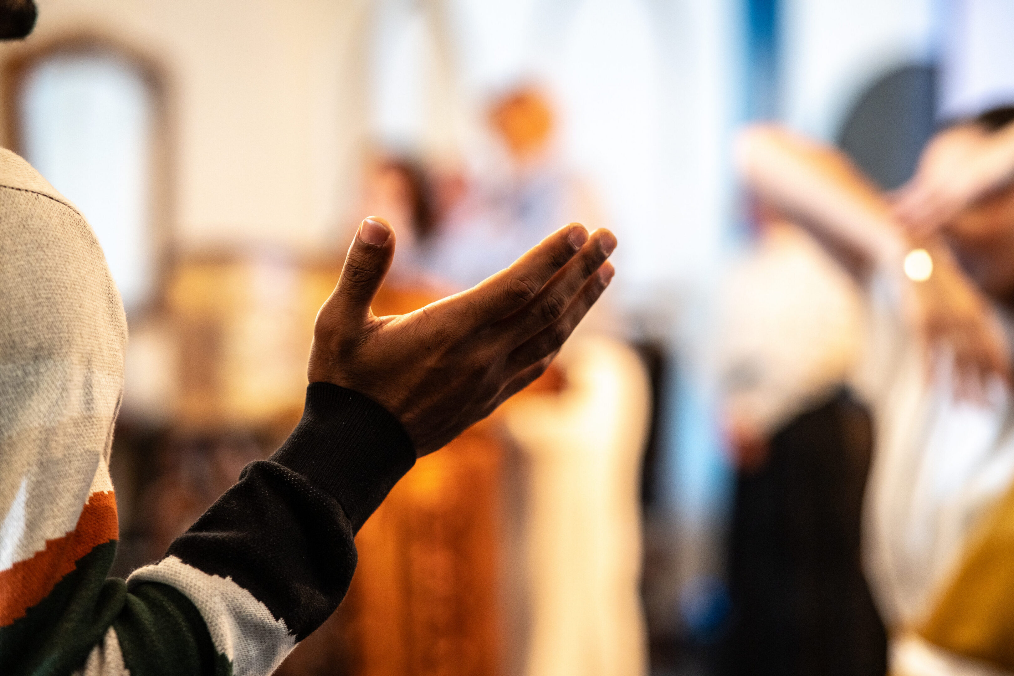 Person's hand raised in a group setting.