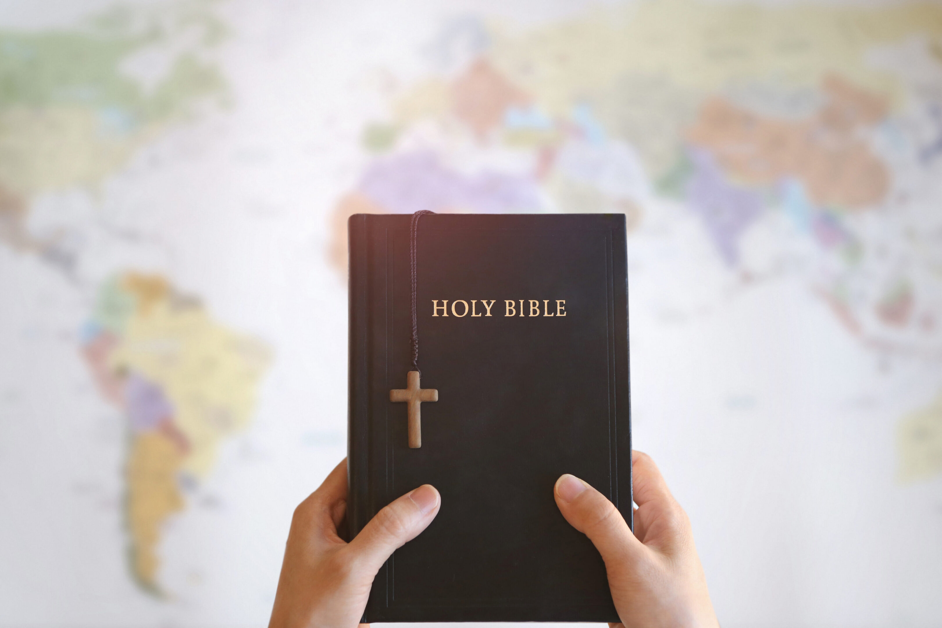 Hands holding a Bible with cross bookmark.