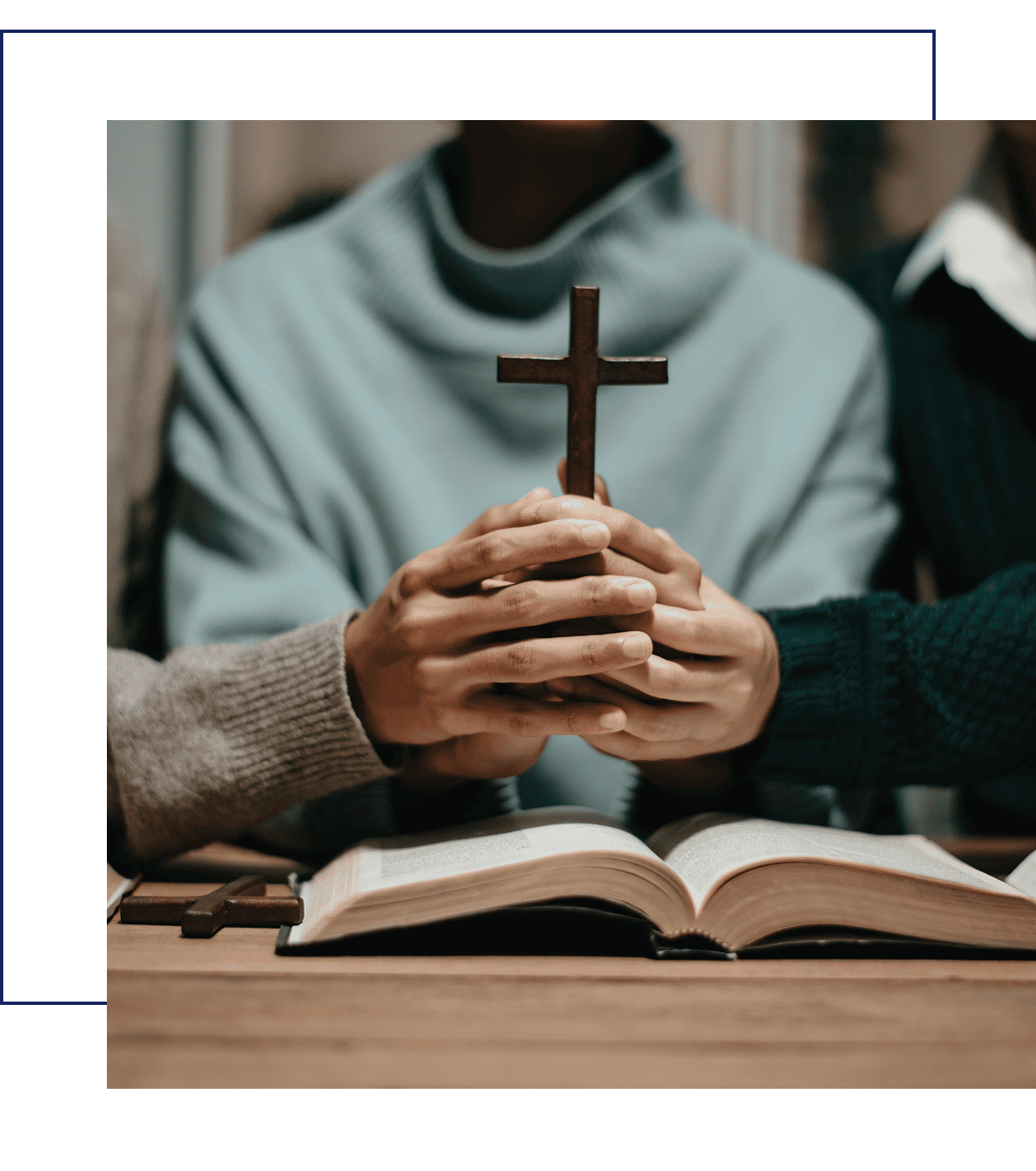 Hands holding cross over open book.