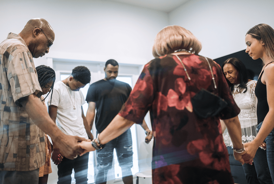 Group holding hands in prayer circle.