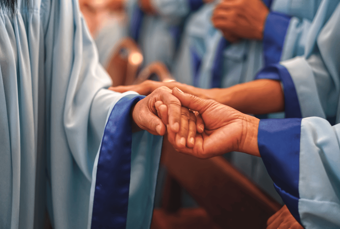 People in robes holding hands during ceremony.